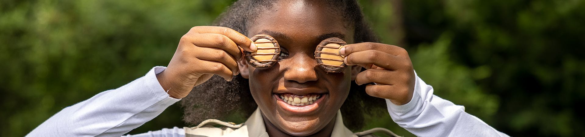  girl scout wearing uniform sash putting trefoil girl scout cookie boxes into cookie transport bag 